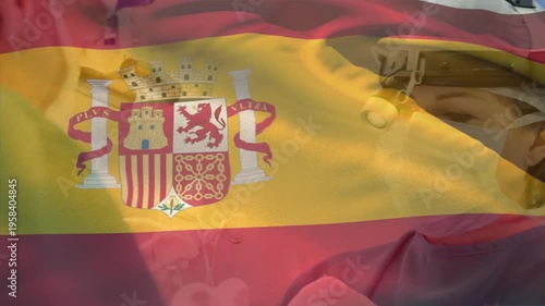 Animation of flag of spain over caucasian surgeons with face masks during surgery