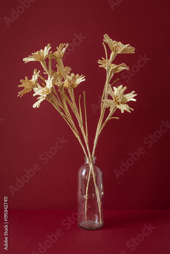 A glass vase with a bouquet of flowers made from straw on the red background. Straw weaving