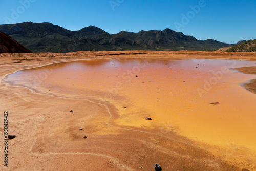 Pit lake with orange hues due to oxidation and mining waste in the mines of Mazarron town