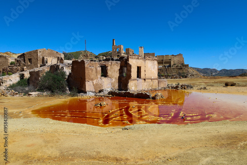 Pit lake with orange hues due to oxidation and mining waste in the mines of Mazarron town