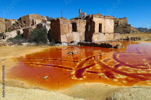 Pit lake with orange hues due to oxidation and mining waste in the mines of Mazarron town