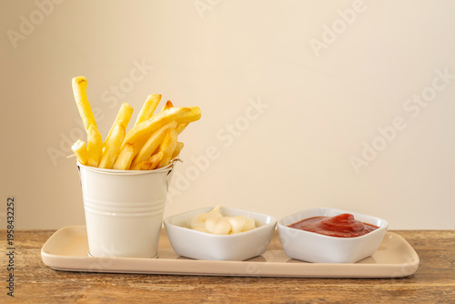 Food background with tasty snack potato chips, mayonnaise, ketchup on wooden table.
