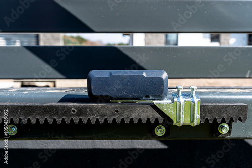 Sliding gate installation with safety sensor and gear rack