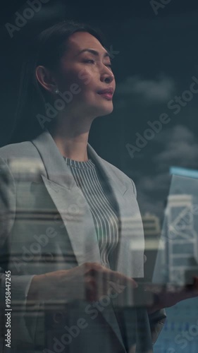 Vertical Screen. Asian Businesswoman in a Light Blazer Stands by an Office Window, Reviewing a Tablet, Looking at Big City Opportunities. Continuing Digital Work With Focus and Determination