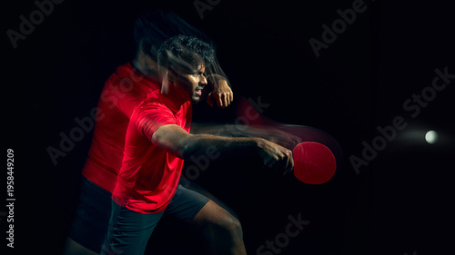 Table tennis player reacting to fast ball with motion blur in dark studio. Concept of reaction speed training, reflex development, quick response ability and athletic performance improvement.