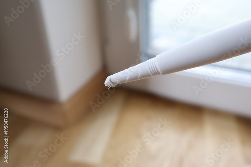 Close‑up of a silicone sealant nozzle used for home repair and construction work. Plastic applicator tip designed for precise application of sealant, adhesive, or caulk during DIY projects,  Poland, k