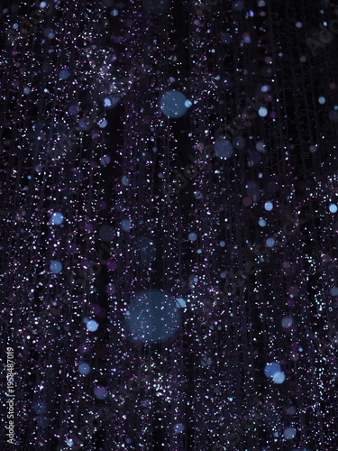 Blue bokeh backgrounds with falling snowflakes and rain drops on the window create a magic winter night design featuring cold water patterns and holiday glitter