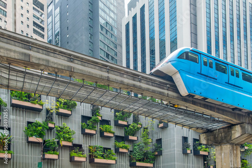 Elevated monorail train moving through central Kuala Lumpur along modern high-rise buildings and green facades. Urban mobility, public transport infrastructure and sustainable city development
