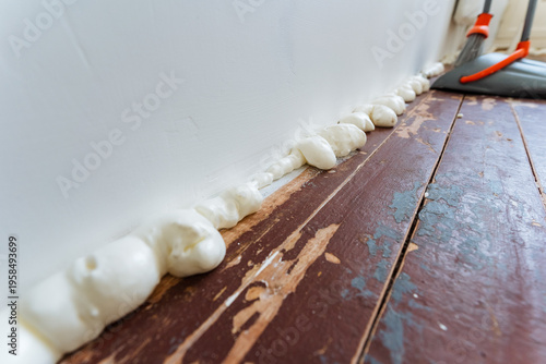 Sealant Fills Gaps. Closeup View Of DIY Repair With Foam And Tools In Background. Scene Showing Homemade Repair Involving Foam For Cracked Flooring And Unsharp Tools In Distance