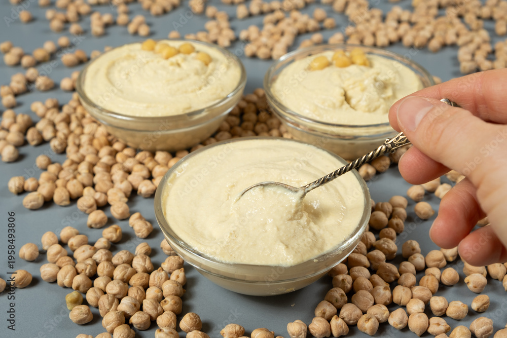 Fototapeta premium Traditional hummus in a spoon among scattered raw chickpeas.