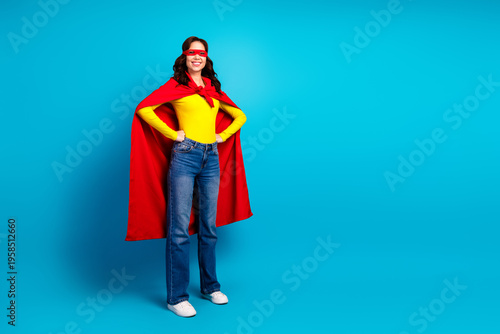 Young woman wearing a red cape and yellow top strikes a confident playful superhero pose