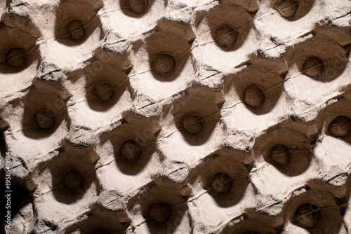 Macro shot of a recycled paper pulp egg tray showing detailed fibrous texture and geometric patterns with high contrast lighting.
