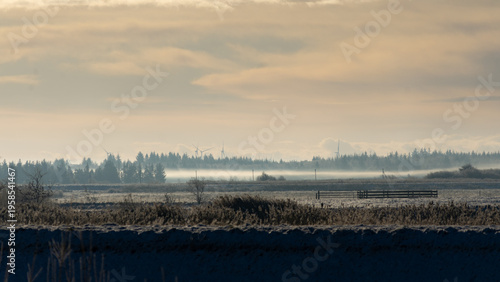 Golden hour at Wadden Sea National Park: Misty winter sunrise over Danish marshland and river 