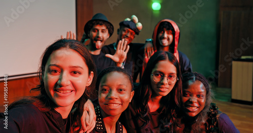 Indian young adult gen z male man female look camera take selfie photos have fun joy hall stage place. Happy teen girl boy group team staring cam do funny pose record video spend day enjoy break time