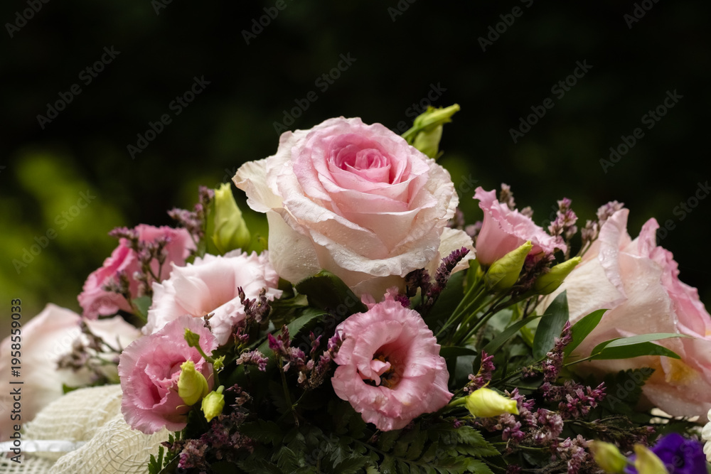 Fototapeta premium Funeral flower arrangement of red and white flowers. Beautiful funeral flowers on a memorial stone in a cemetery. Blurred background. Empty space for text.