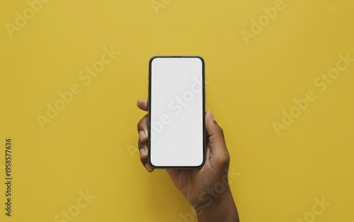 Hand holding smartphone with blank screen on yellow background