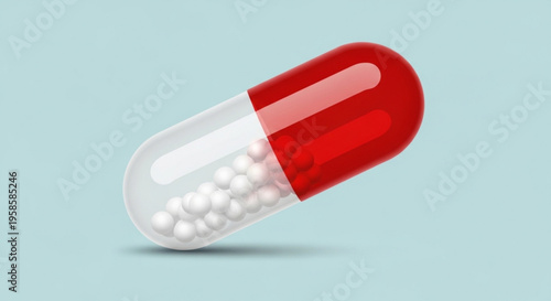 Close up of a red and white medical capsule with small pills inside on a light blue background representing health and medication