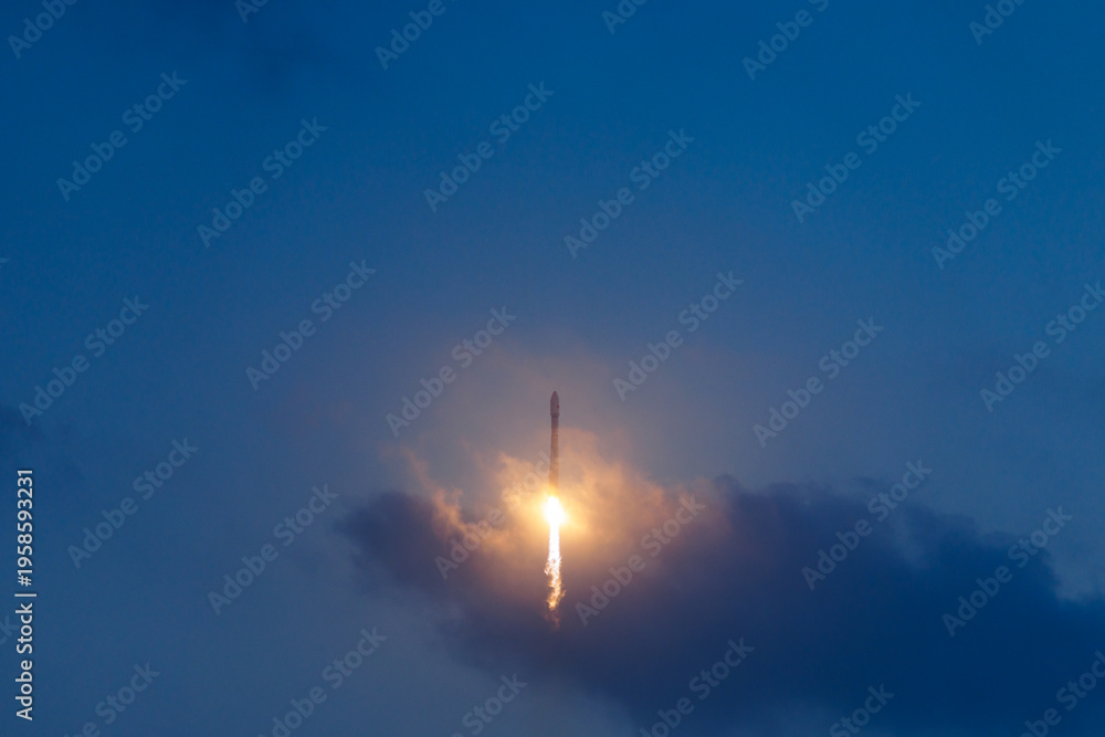 Fototapeta premium Rocket launch against evening sky with dramatic cloud and smoke and flame trail