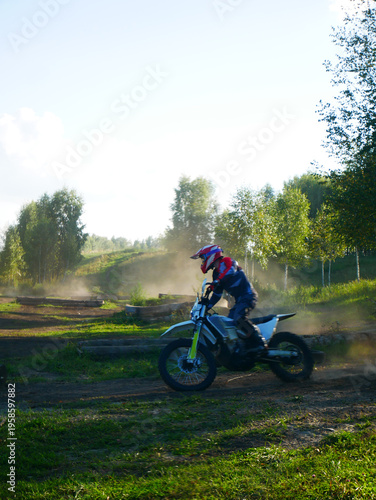 Motocross rider driving motorcycle on track. Man in protective gear racing dirt bike through summer forest. Extreme sport, speed, competition, active hobby, outdoor adventure concept.