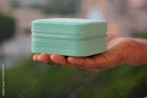 Hand Holding Closed Mint Green Jewelry Box Outdoor Lifestyle Shot