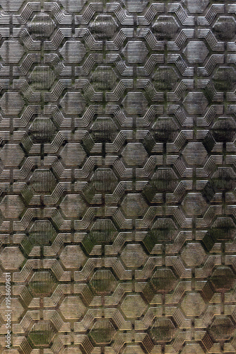 Textured patterned window glass with geometric hexagonal design, abstract background with metallic look, modern architectural surface with copy space.
