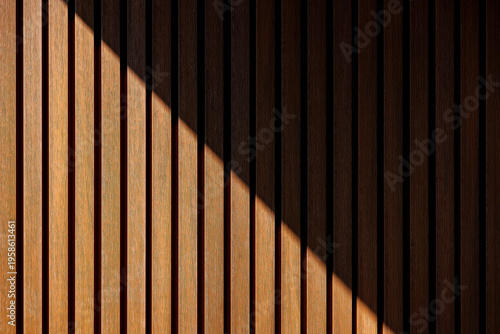 Natural wooden slats arranged in an organic pattern with partial sunlight, suitable as a background or texture.