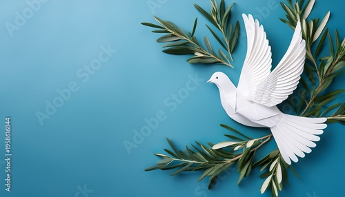 Top view of white paper dove decoration with olive tree branches on pale blue background with copy space
