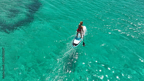 Aerial drone photo of fit unidentified woman paddling on a SUP board or Stand Up Paddle board in deep blue sea