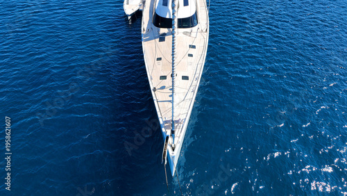 Aerial drone photo of beautiful luxury sail boat with wooden deck anchored in deep blue Mediterranean sea 