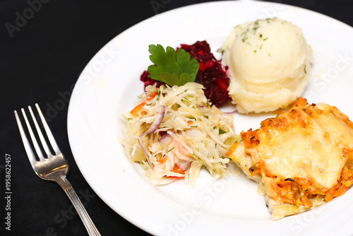 Fotografie Plate with mashed potatoes cabbage salad and baked dish on dark background