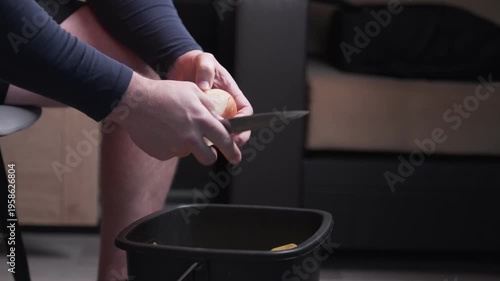 Men's hands peel onions with a knife. The cook's hands peel the onion from the husk.