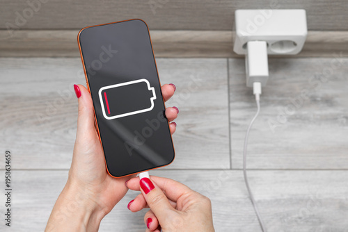 Close-up of a woman's hands charging a smartphone using a cable and USB port. A woman charges a smartphone, close-up. dead smartphone battery. discharged battery