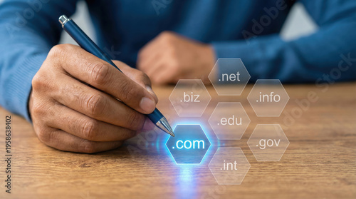 man hand holding blue pen pointing to com domain on wooden desk with hexagons