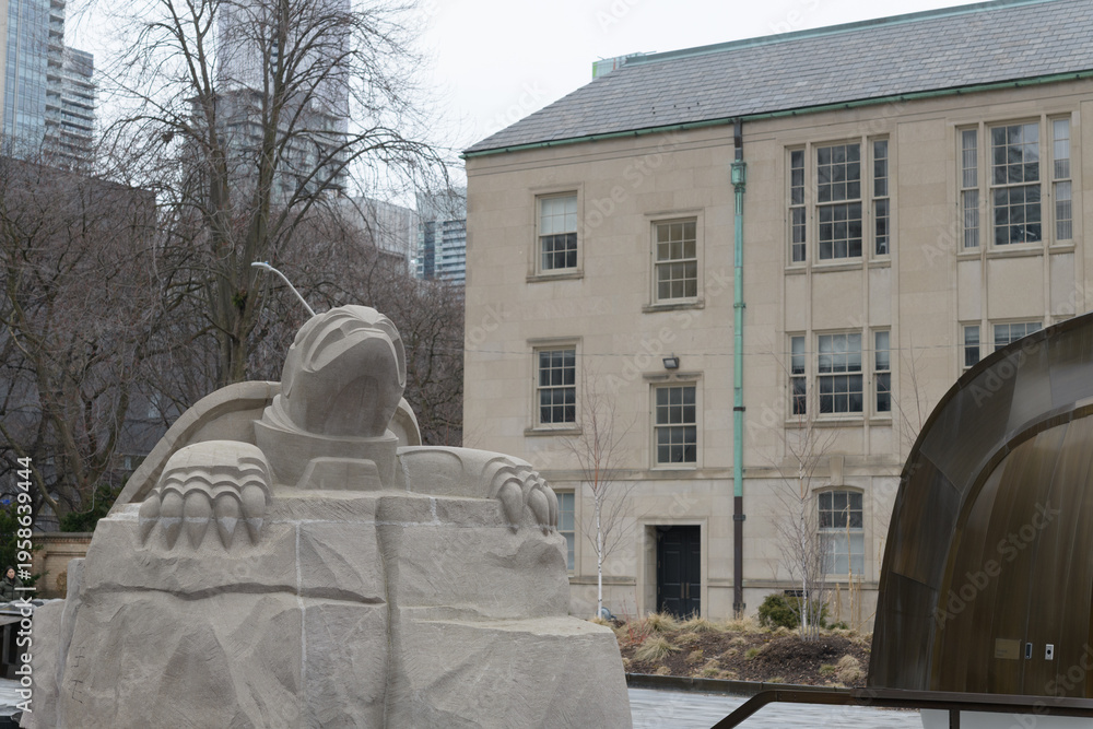 Fototapeta premium six-foot limestone turtle by Solomon King anchors the Spirit Garden, symbolizing Turtle Island and residential school remembrance; it sits in a reflecting pool aligned to Magnetic North, Toronto