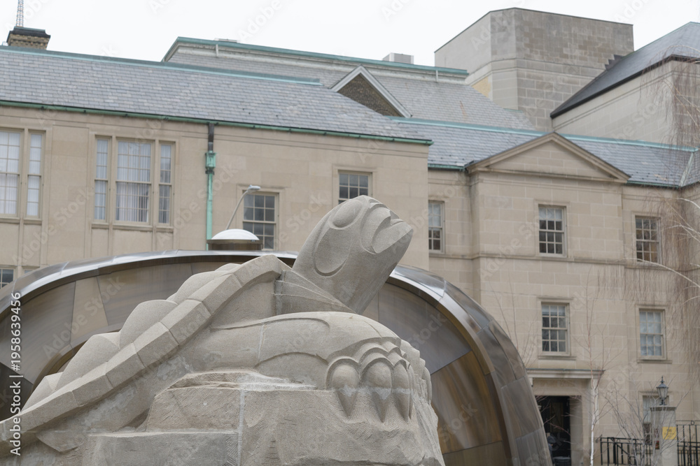 Fototapeta premium six-foot limestone turtle by Solomon King anchors the Spirit Garden, symbolizing Turtle Island and residential school remembrance; it sits in a reflecting pool aligned to Magnetic North, Toronto