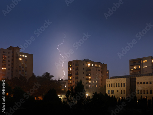 Konstfotografi Powerful lightning strike illuminates the night sky above residential apartment