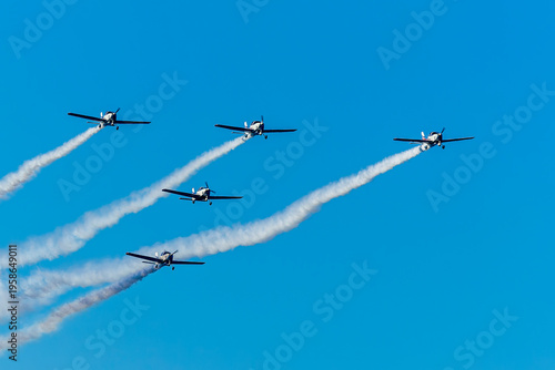Group of aircraft planes in flight during airshow. Jets flying in the air. Airborne sport in thr sky with airplanes with blue background.