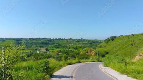Empty Rural Roadway with Yellow Lines and Green Fields Under Blue Sky