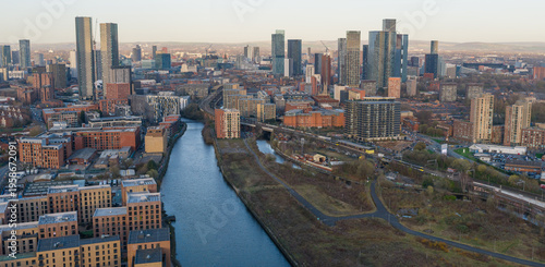 A wide panorama showing the River Irwell, the Metrolink line at Pomona, and the high-rise skyline including Deansgate Square and Castlefield, UK.