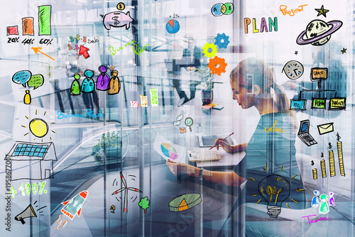 Professional woman works on business planning with digital sketches on glass walls in office during daytime