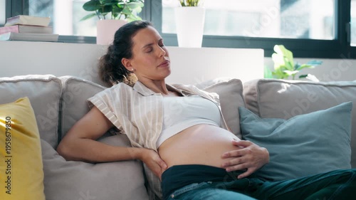 Video of pregnant woman with back pain and sciatica sitting on the couch at home