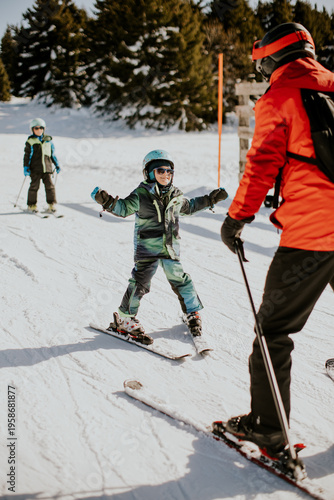 Child learning to ski with instructor on snowy slope at winter resort in daytime
