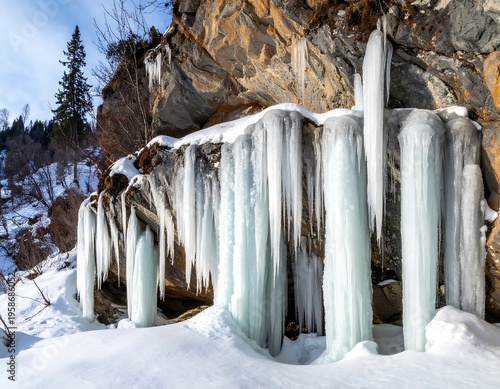 Towering icicles hang off a rocky outcropping covered in snow on a cold winter day