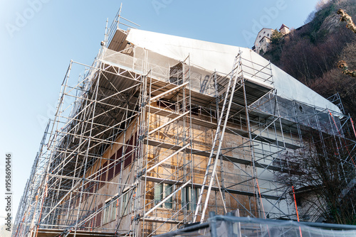 Building facade covered with metal scaffolding during renovation and restoration work. Urban construction and infrastructure development concept highlighting progress, engineering