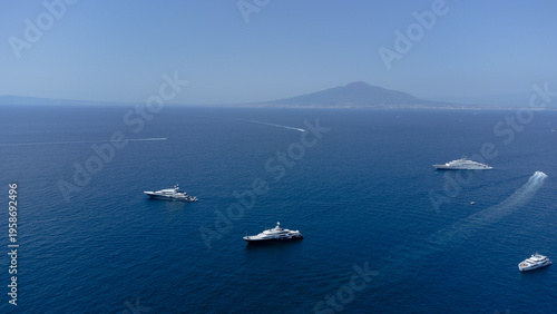 Bild auf Leinwand Luxury Yacht Fleet Glides Across Azure Seas with Distant Island Horizon