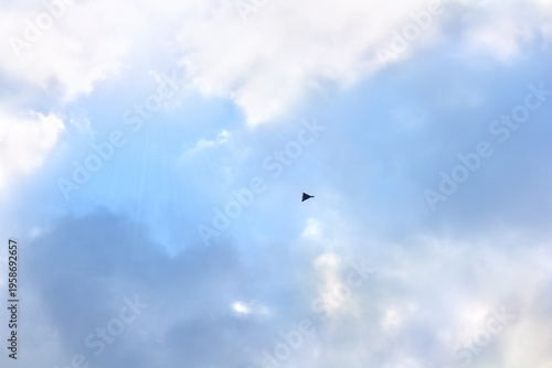 Shahed type kamikaze drone flying in blue sky with clouds, black loitering munition, unmanned aerial vehicle (UAV) in flight