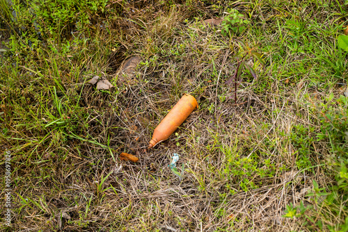 Close‑up of plastic debris scattered among wet grass and soil, highlighting environmental pollution, human impact on nature, and the contrast between natural textures and artificial waste.