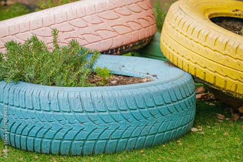 Colorful recycled tires used as garden planters with green plants in creative outdoor landscaping design