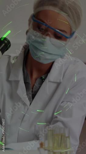 Vertical video: Tech reaching tube, checking using scope while particles across bench for lab tests