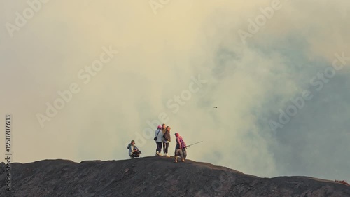 Small group of people hiking on the mount bromo volcano crater rim